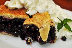 Piece of fruit pie with whipped cream and mint leaves