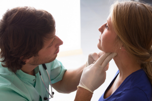 Photo of a nurse looking at a womans neck