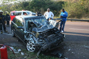 Men standing by the scene of a motor vehicle accident
